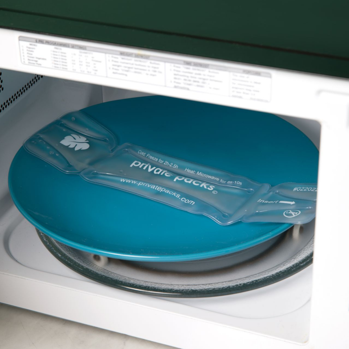 Private Packs hot and cold therapy pad warming in microwave on plate.